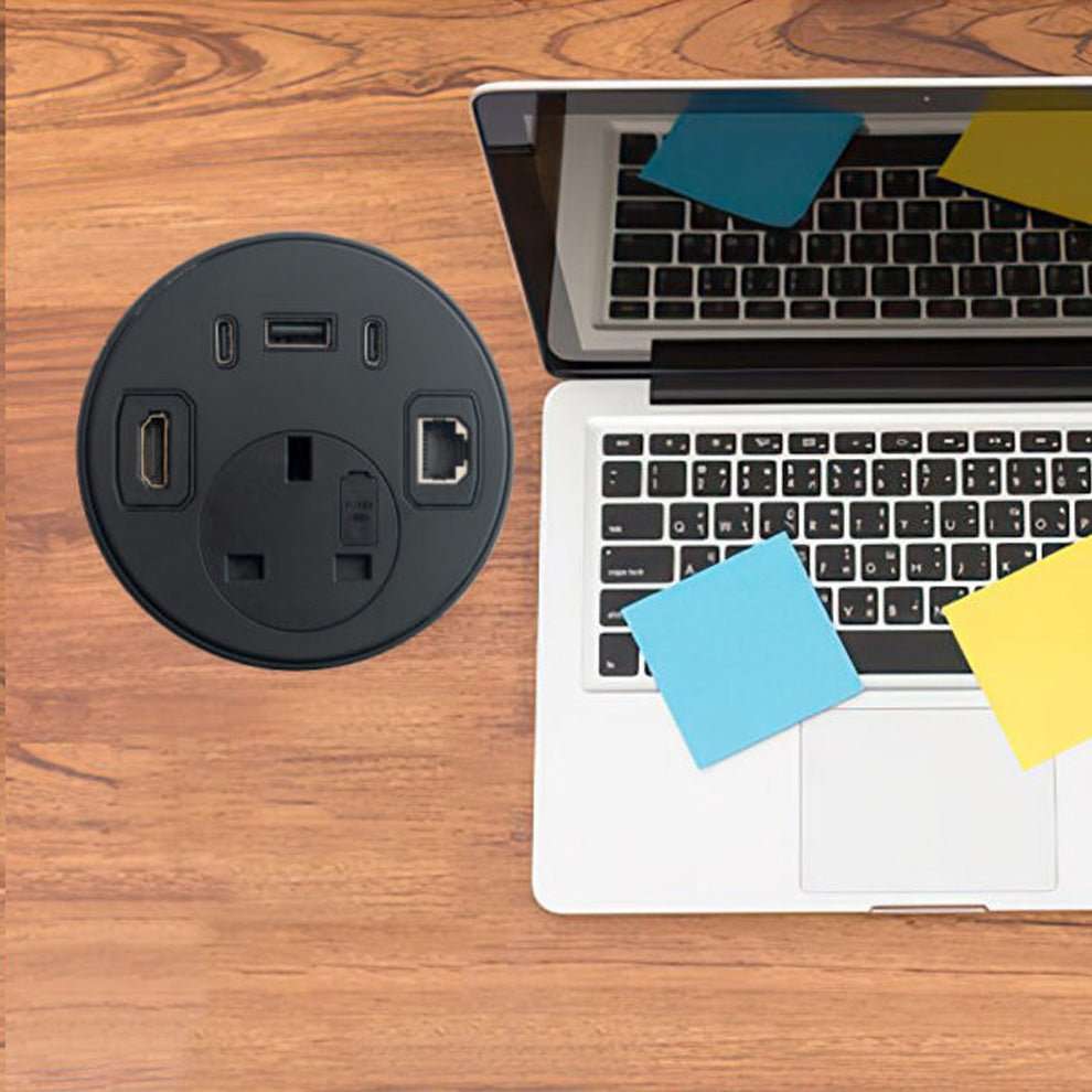 Power outlet and laptop on wooden desk
