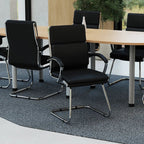 Modern conference room with black chairs and a round wooden table.