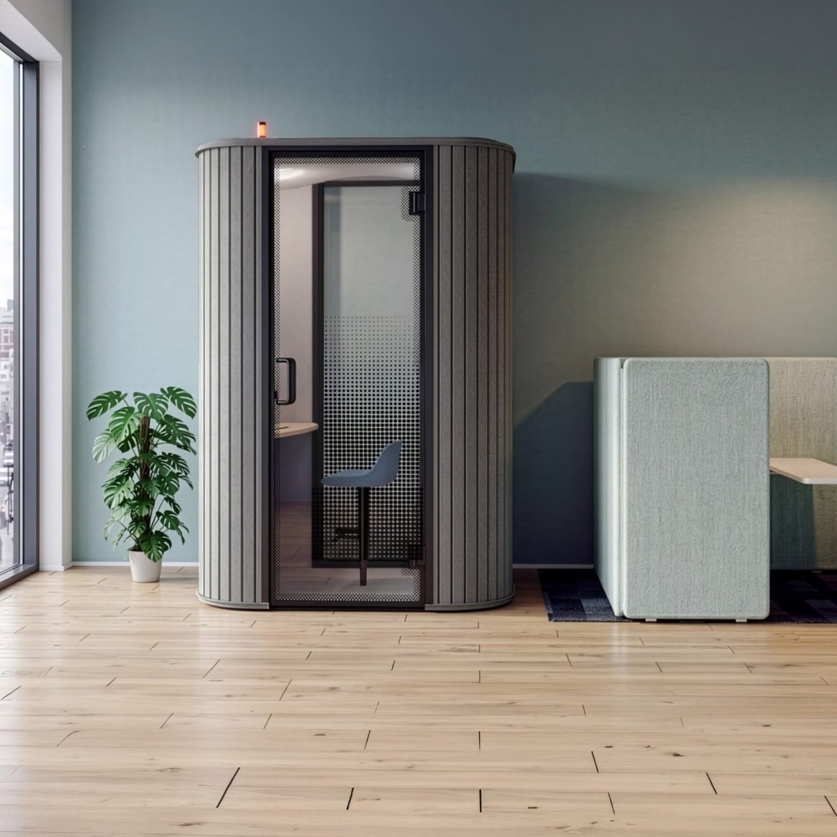 A modern privacy call room with a fluted gray exterior and frosted glass door, set in a minimalist office space with a city view, a potted plant, and a seating area.