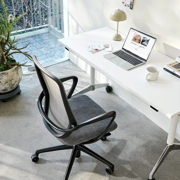 Modern office setup with a desk, chair, and laptop in a bright room.