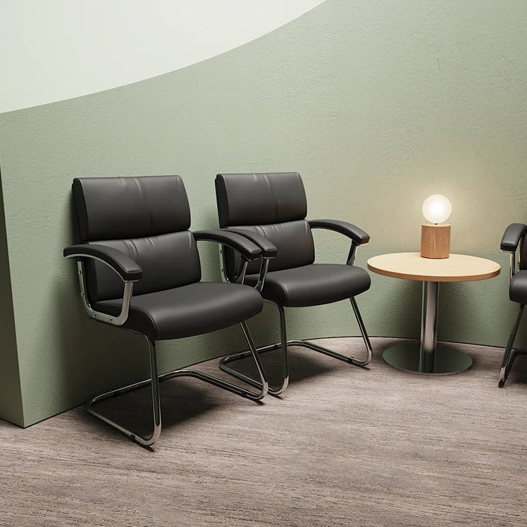 Modern waiting room with black leather chairs and a small round table.