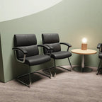 Modern waiting room with black leather chairs and a small round table.