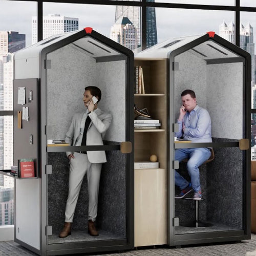 Two people using office pod booths with a cityscape view outside.