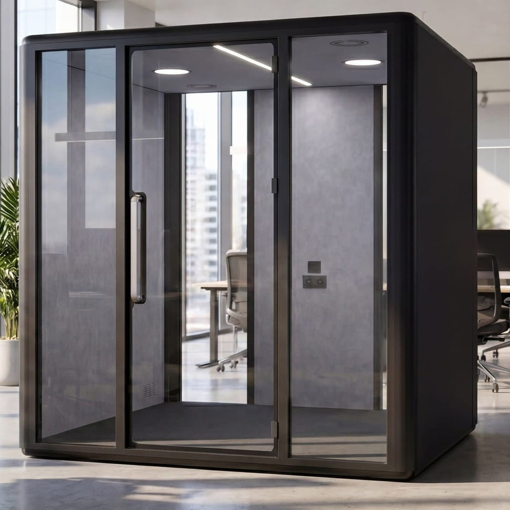 A modern black glass privacy booth with a solid back wall, shown in a bright, contemporary office environment with desks and office chairs.