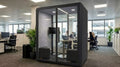 Modern office with a glass partitioned office pod and people working in the background.